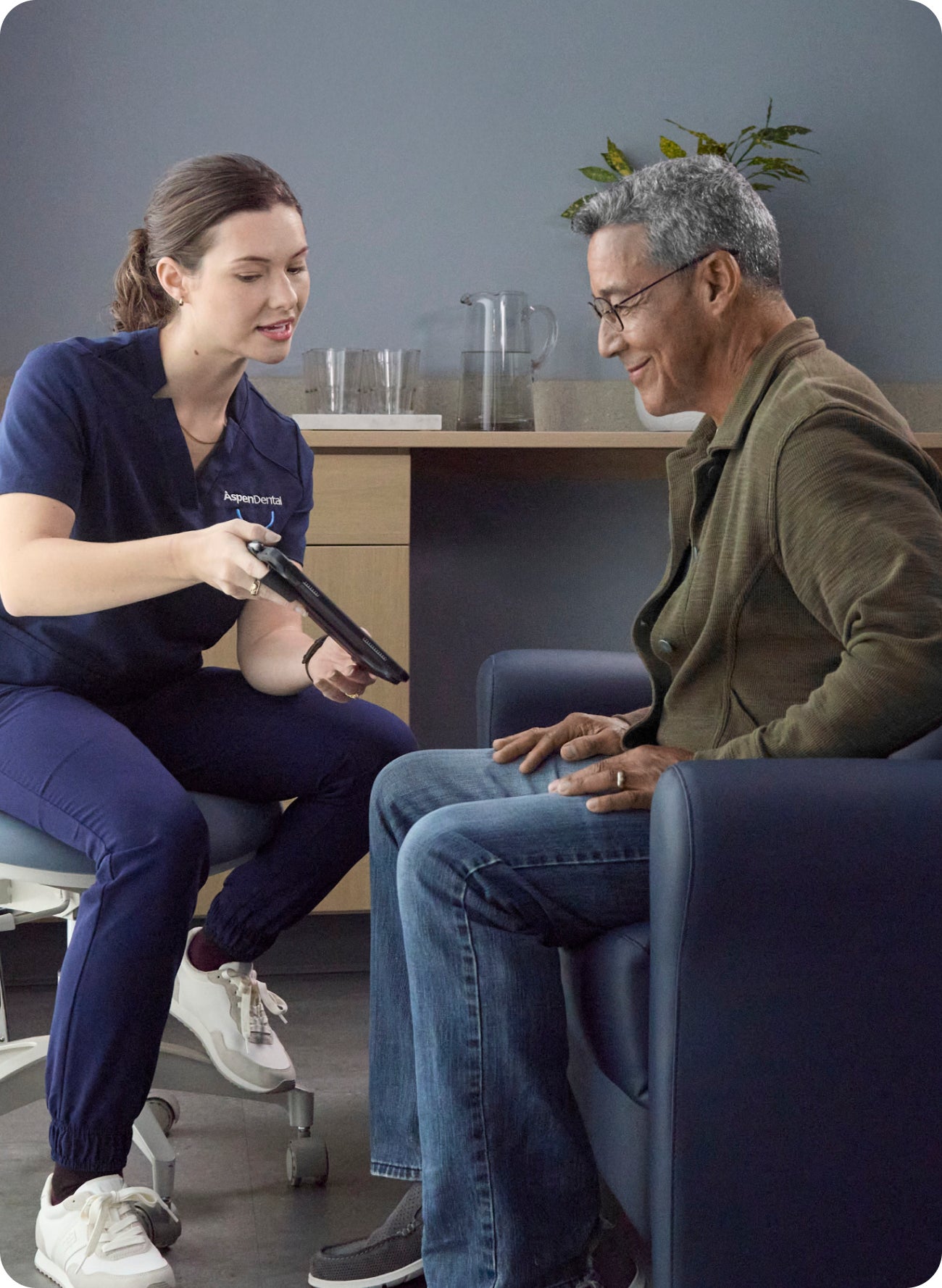 Dental team member discusses emergency visit options with a patient in a dental office, suggesting questions about dental insurance coverage.