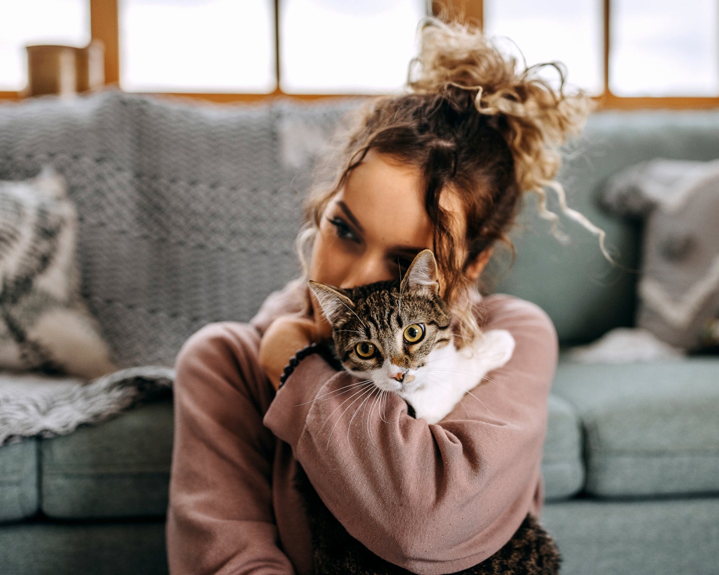 A pet parent hugging a tabby cat.