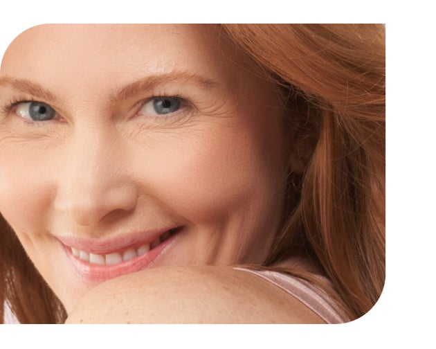 A smiling redhead with blue eyes looks over her shoulder