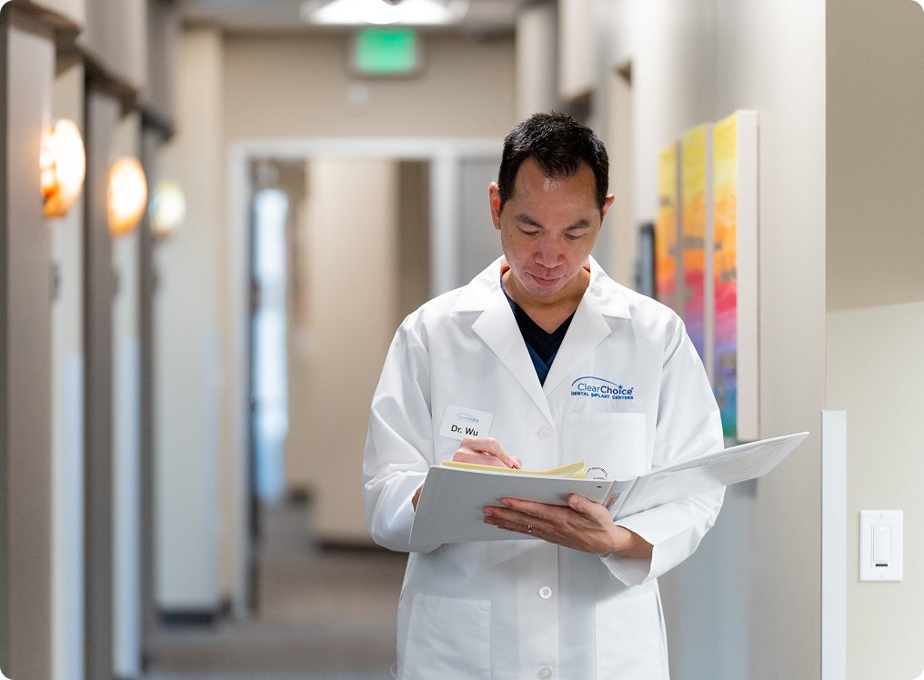 A ClearChoice provider reviewing a patient’s medical history in a hallway, preparing to evaluate dental implant eligibility during a consultation.