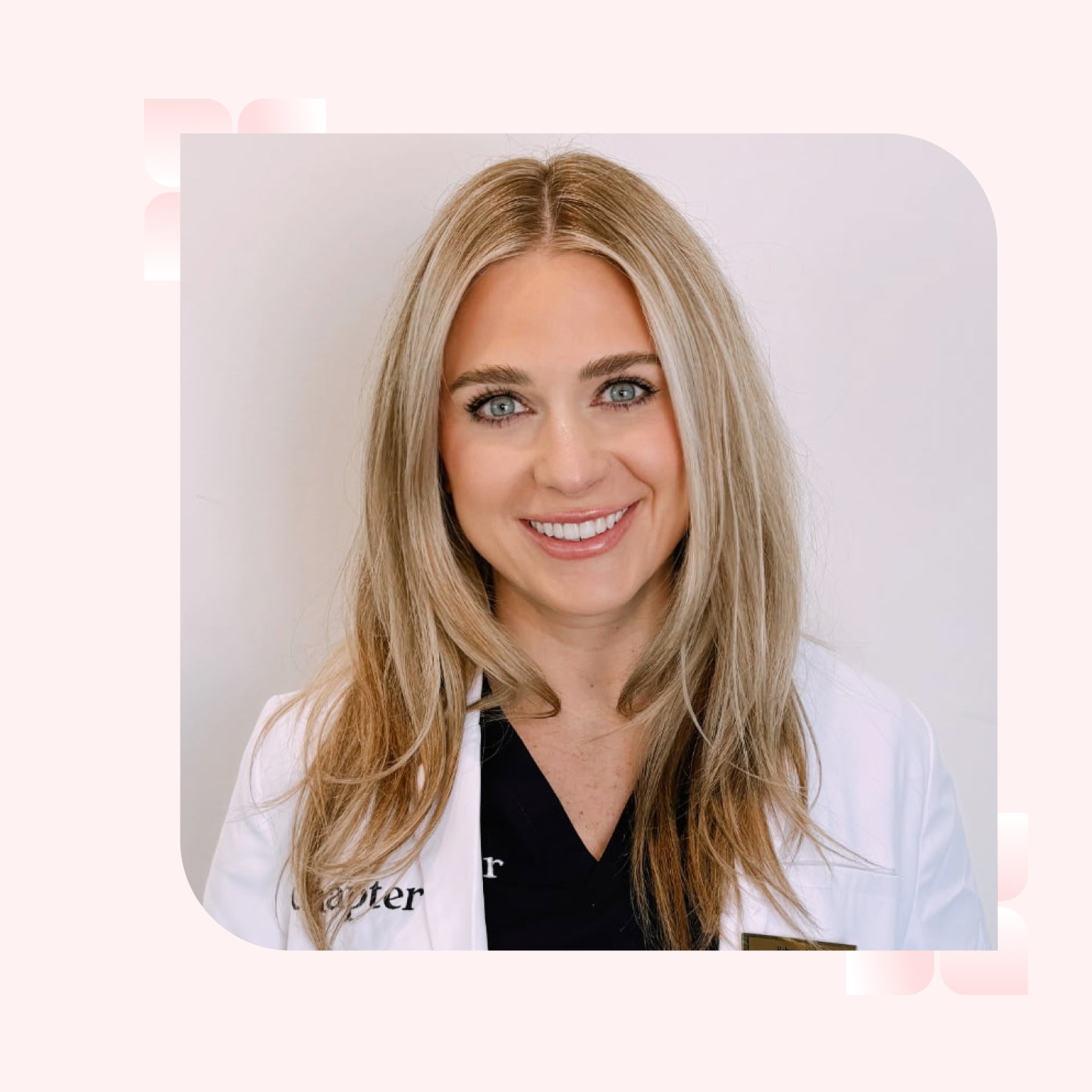 A woman with shoulder length blonde hair smiles, wearing a white lab coat