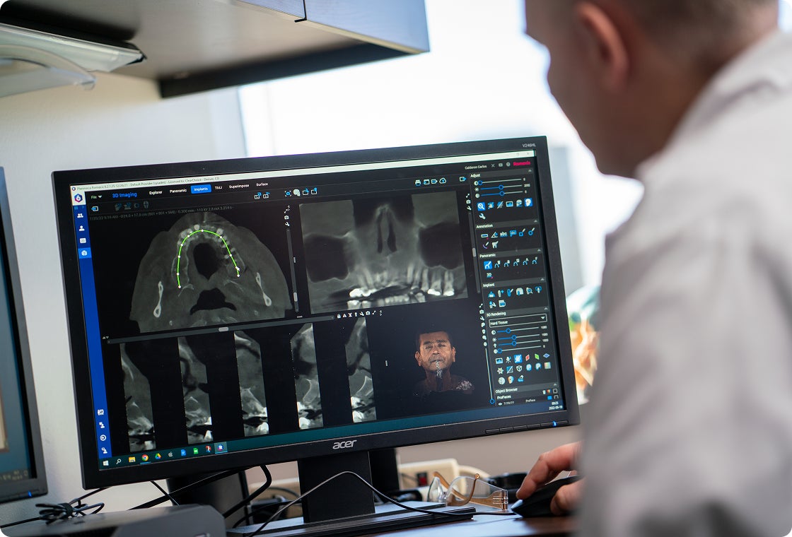 A ClearChoice prosthodontist examines a patient's scan results and teeth structure while outlining his custom treatment plan.