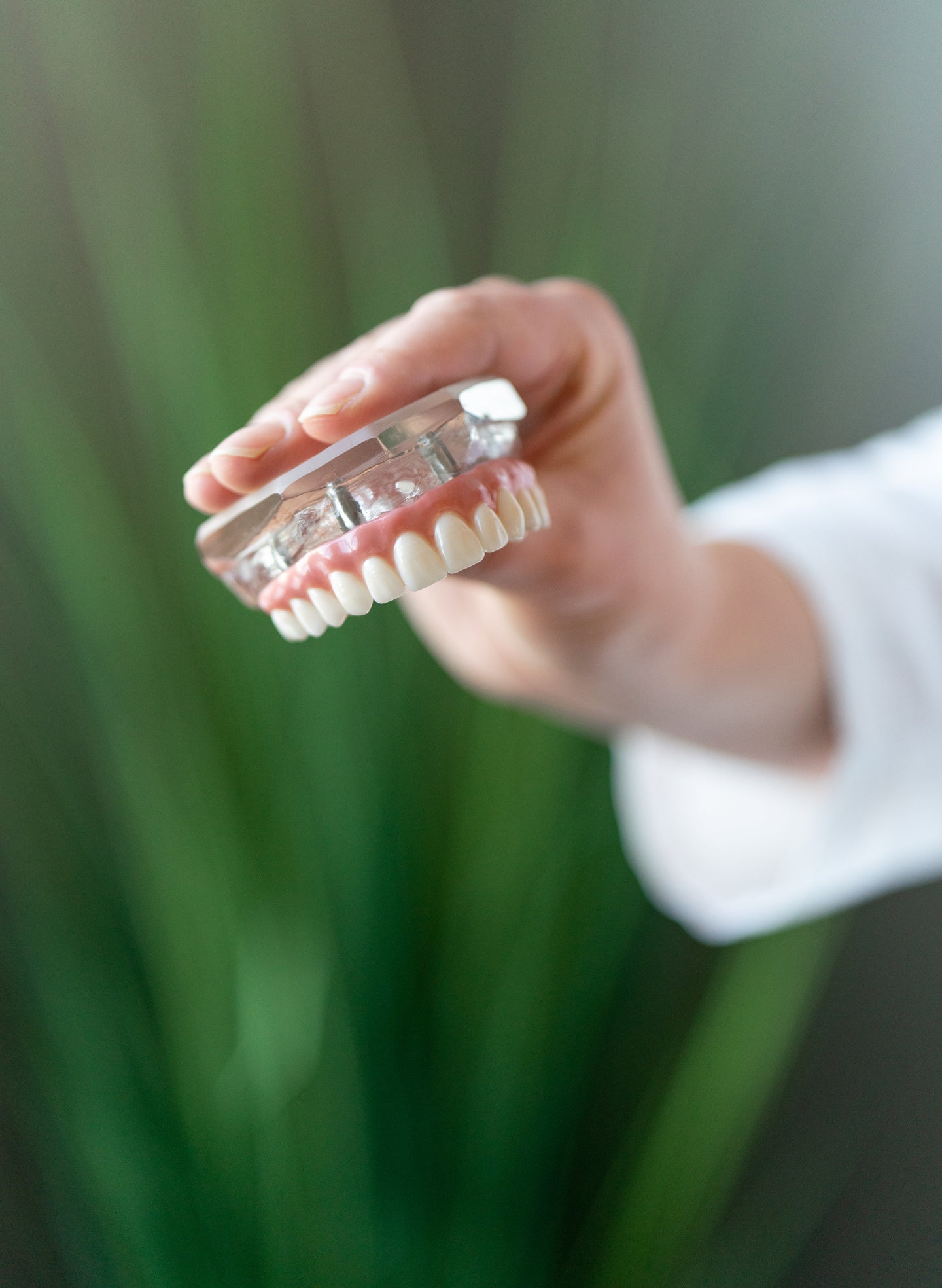 A ClearChoice prosthodontist holding an upper arch dental implant model with four implants.