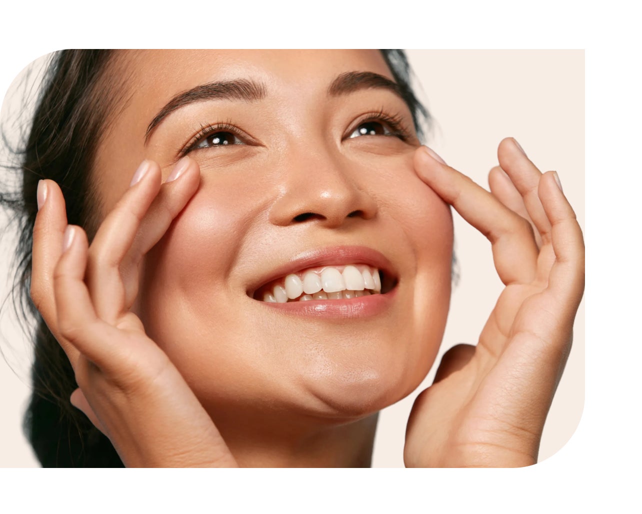 Smiling woman gently touching her radiant skin