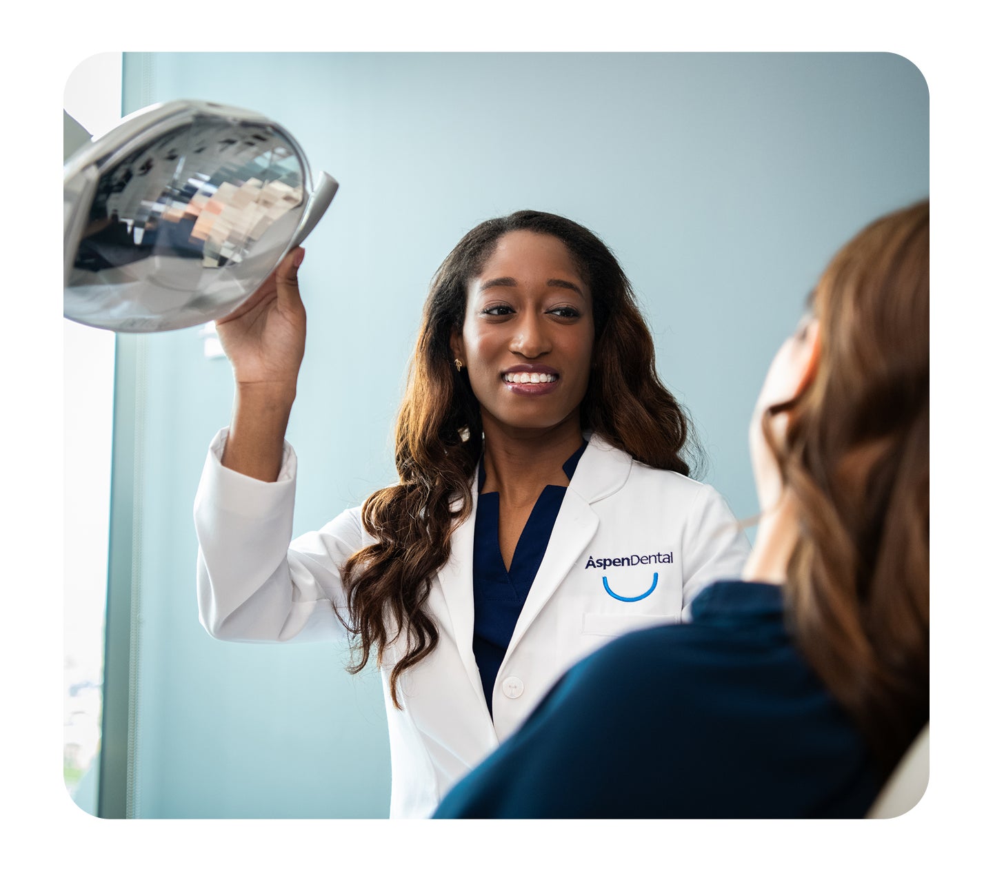 An Aspen dental provider smiles while looking at a patient who is sitting in a dental chair
