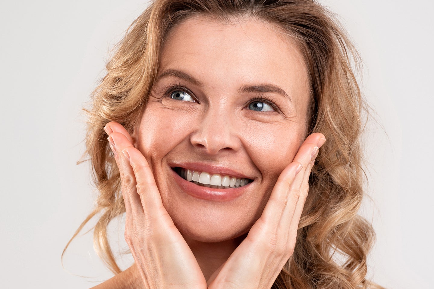 A joyful woman with hands on her cheeks, looking upwards
