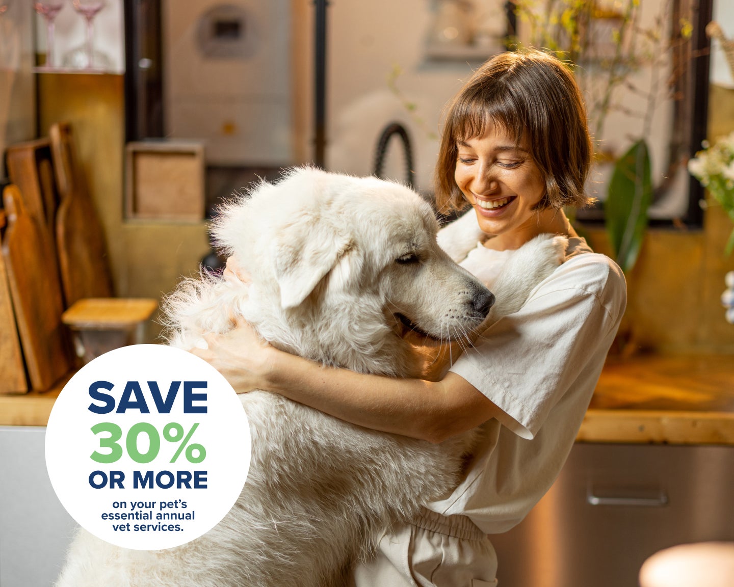 A pet parent dances with their Great Pyrenees in a kitchen with warm lighting.