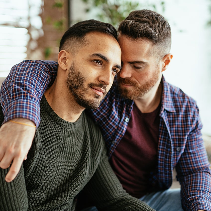 A male presenting same-sex couple embraces in a moment together.