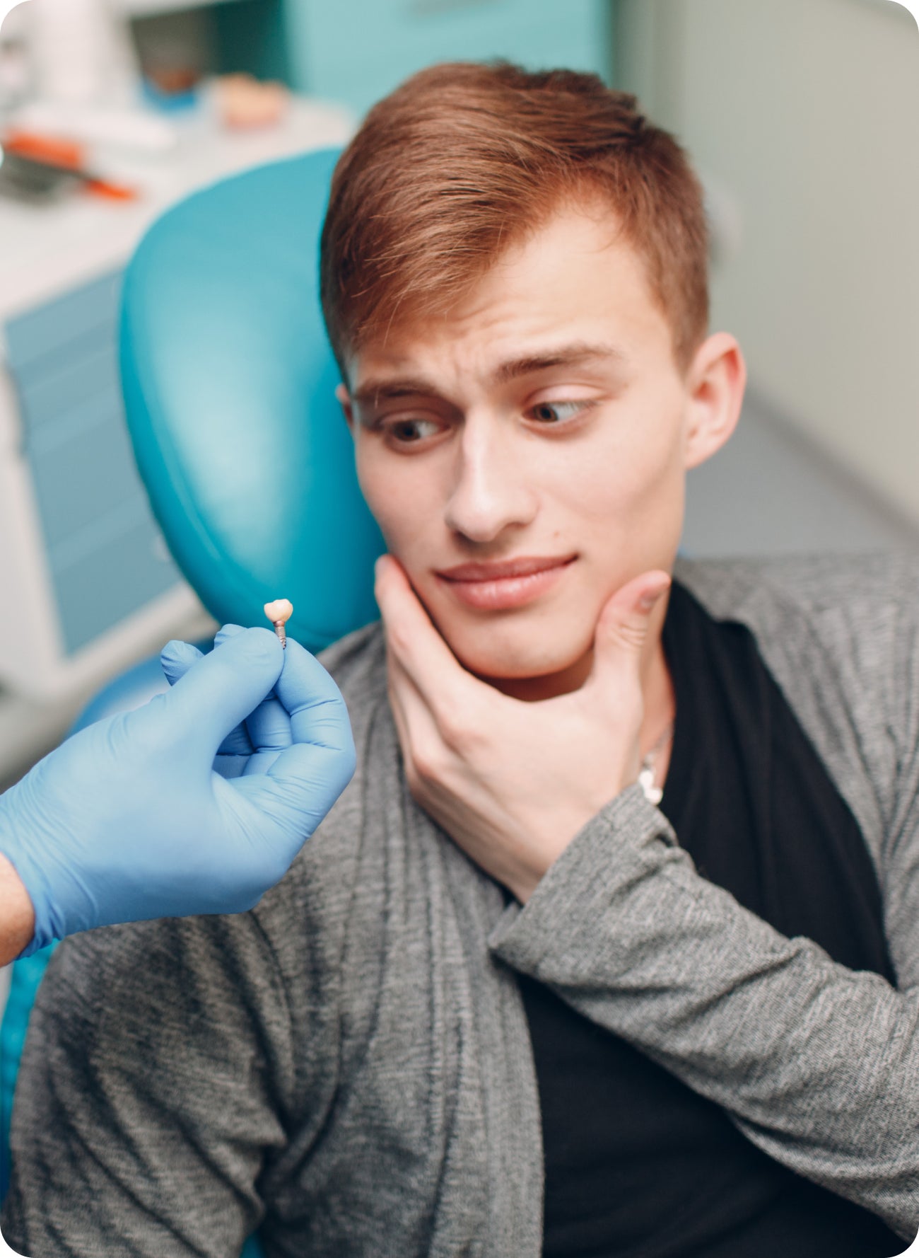 Apprehensive patient looking at a dental crown held by a gloved hand