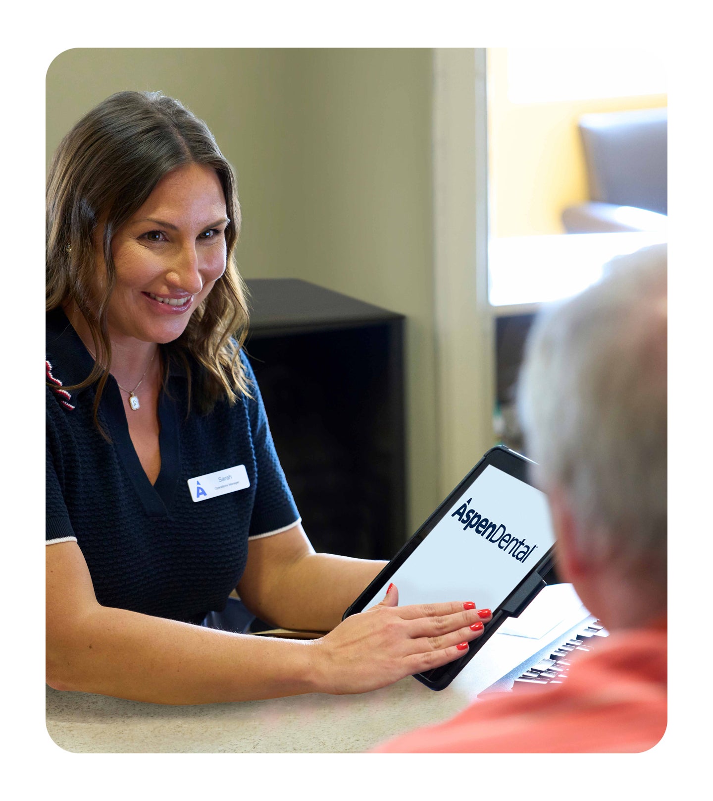 Aspen Dental staff member using a tablet at the front desk in a modern office setting