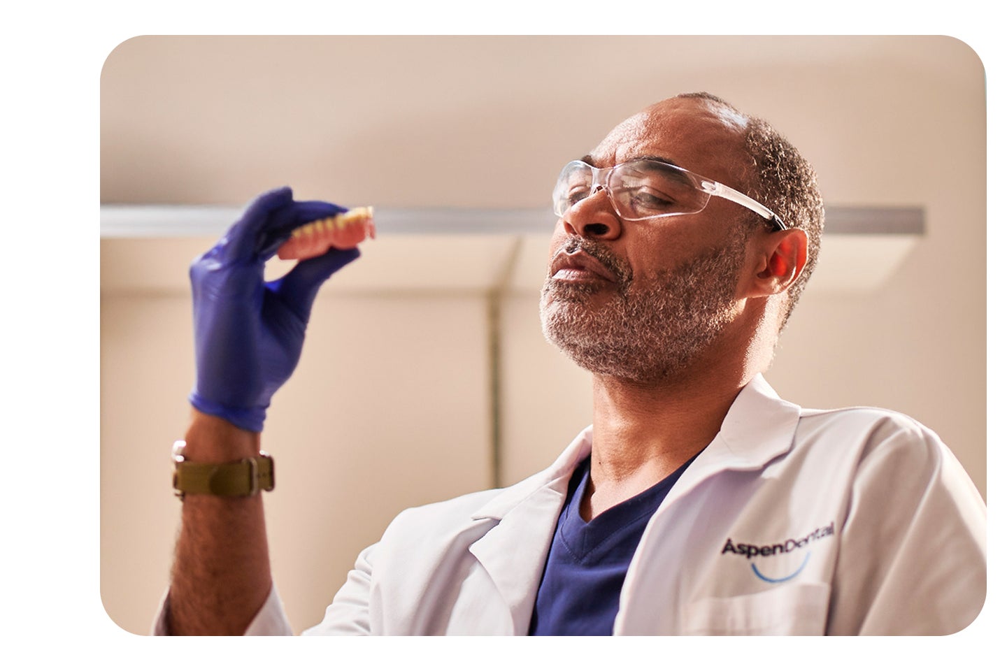 A man in a lab coat is holding a tooth in his hand