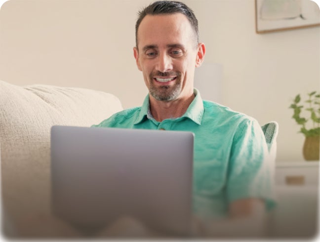Man using laptop at home with text “Implant resources – Your questions, answered” promoting ClearChoice dental implant patient resources.