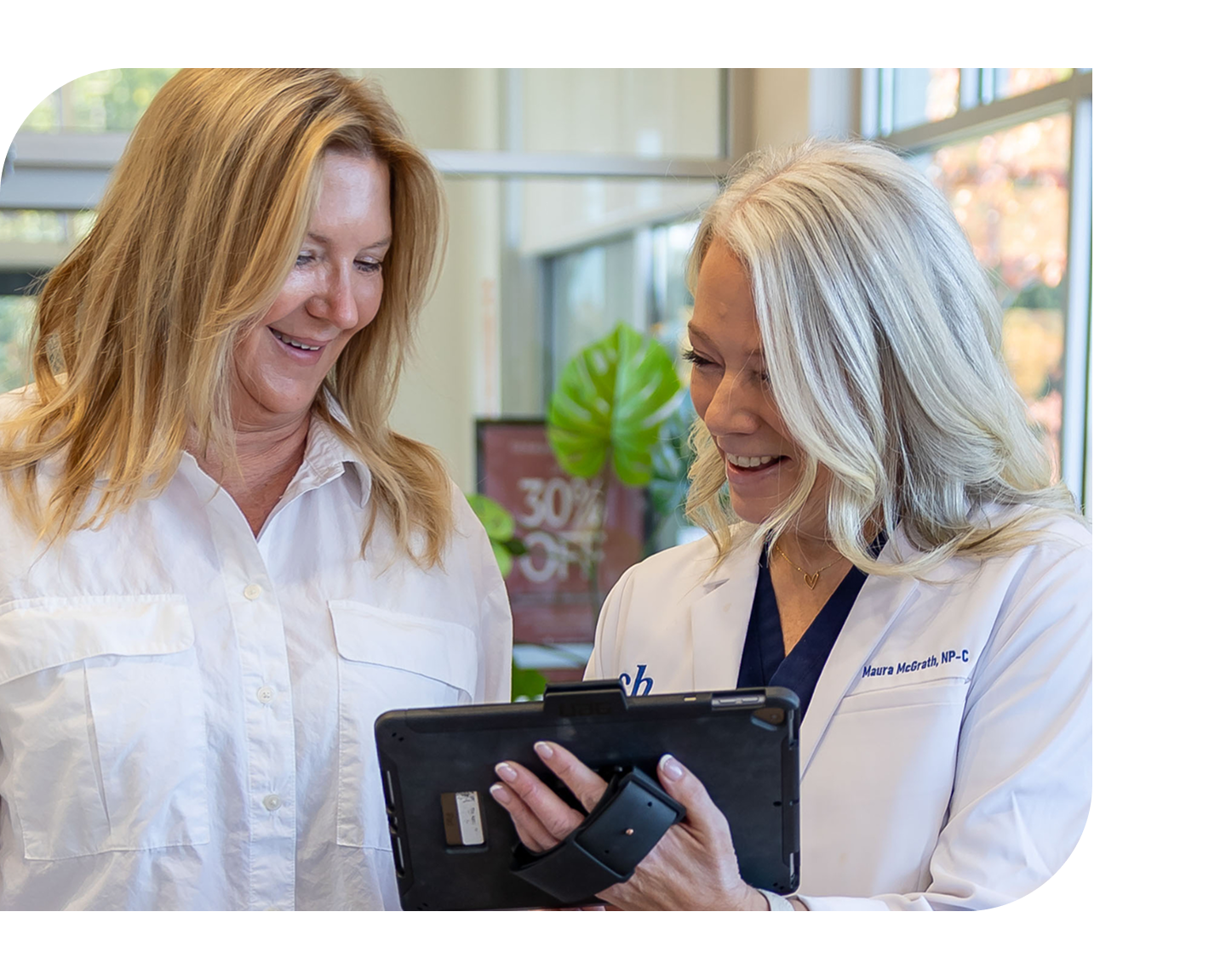An aesthetic provider reviews a tablet with a patient in a bright clinic, highlighting easy access and convenient care.
