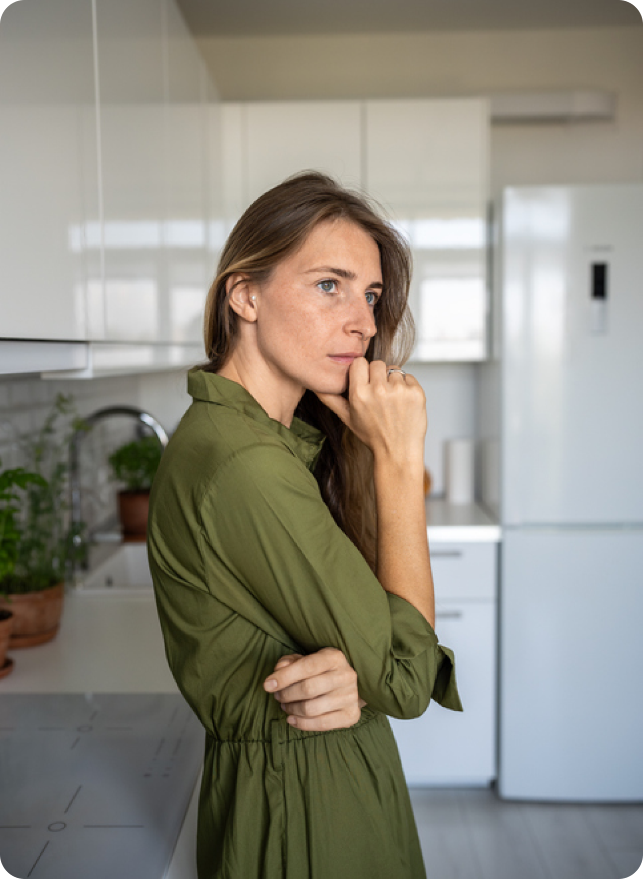 Woman standing with a concerned expression and holding her chin, suggesting one-sided migraine pain that may be related to a bad tooth.