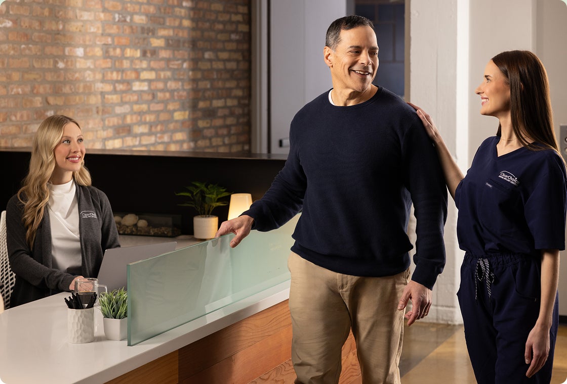 A ClearChoice care team member accompanies a patient to the front desk as they learn that they qualify for the Insurance Assurance program, which offers $5,000 off fixed full arch treatment when their dental insurance doesn’t cover implants.