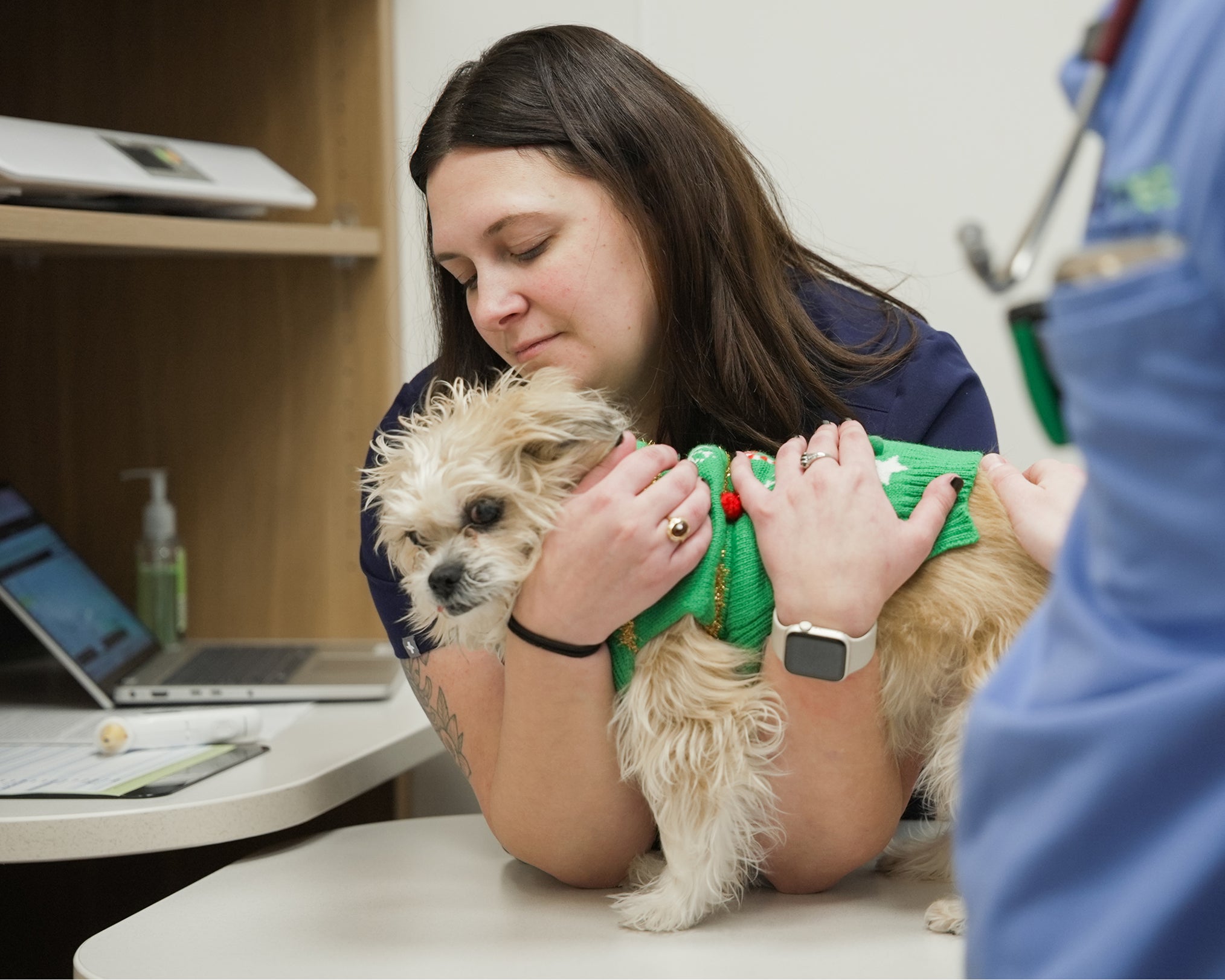 A woman comforts her dog during a veterinary visit