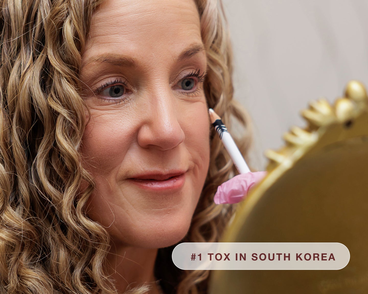 Woman looking im mirror while medical professional marks her face with a white pencil for botox placement.