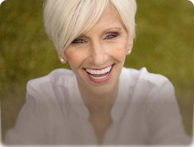 Smiling woman with overlay text: “Implant dentures. Secure fit, for your budget.”