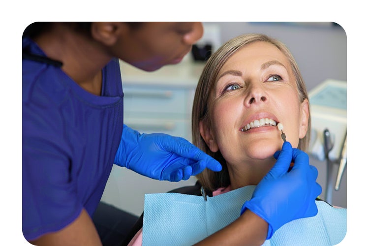 A dentist examining a female patient’s teeth during a dental veneers consultation, showcasing personalized cosmetic dentistry care and a confident smile.