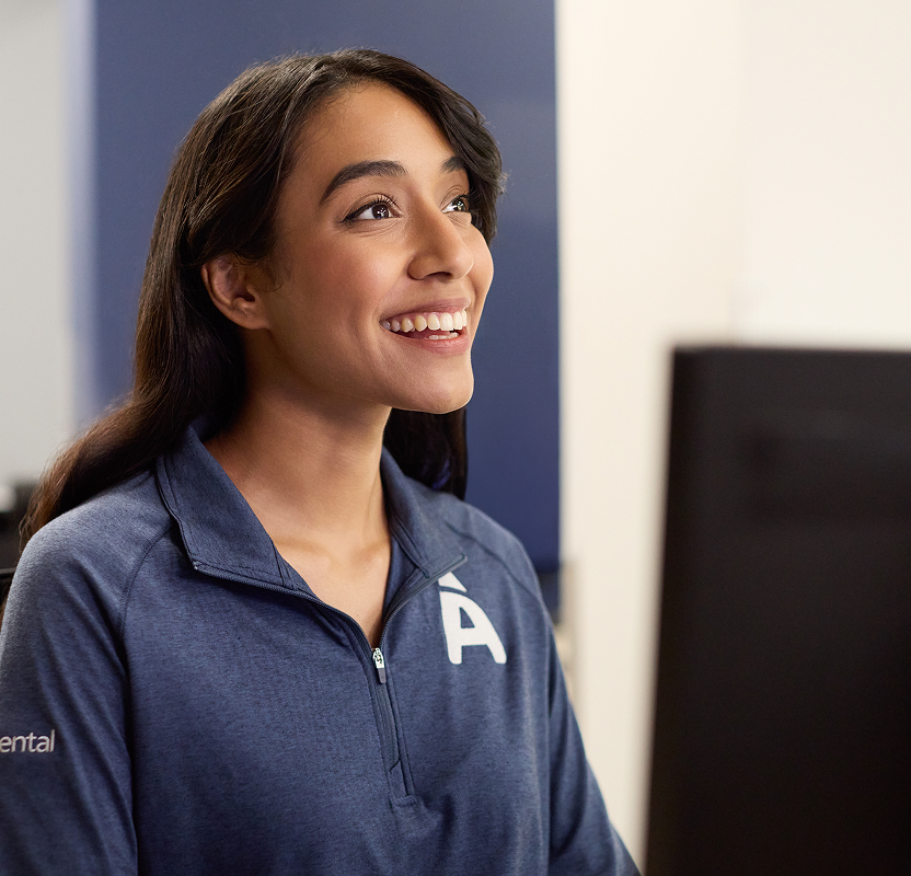 Smiling dental office team member assisting a patient at the front desk.