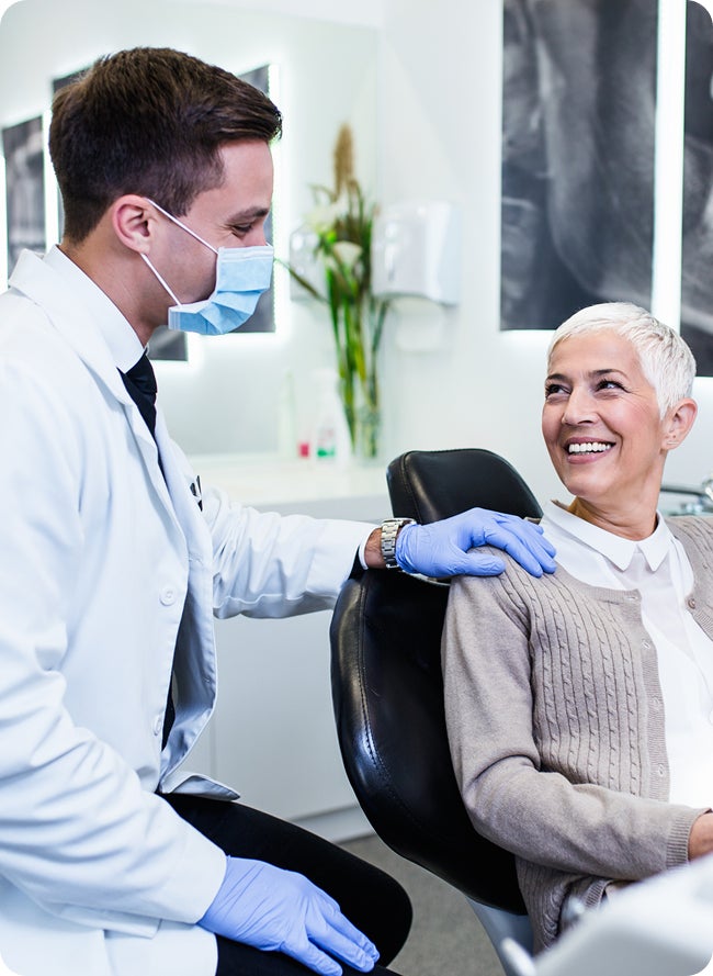 Dentist talks with a smiling patient in a dental chair about eating after a root canal. Focus on post-treatment care and dietary guidance.