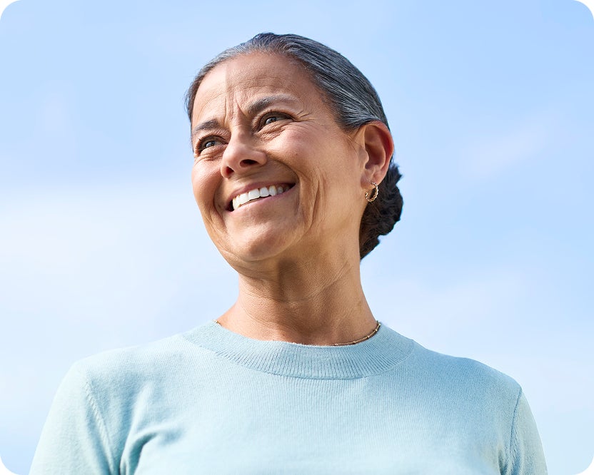 Smiling woman looking joyfully towards the blue sky