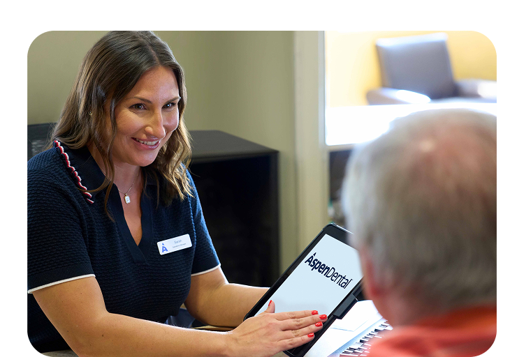 Aspen Dental staff member using a tablet at the front desk in a modern office setting