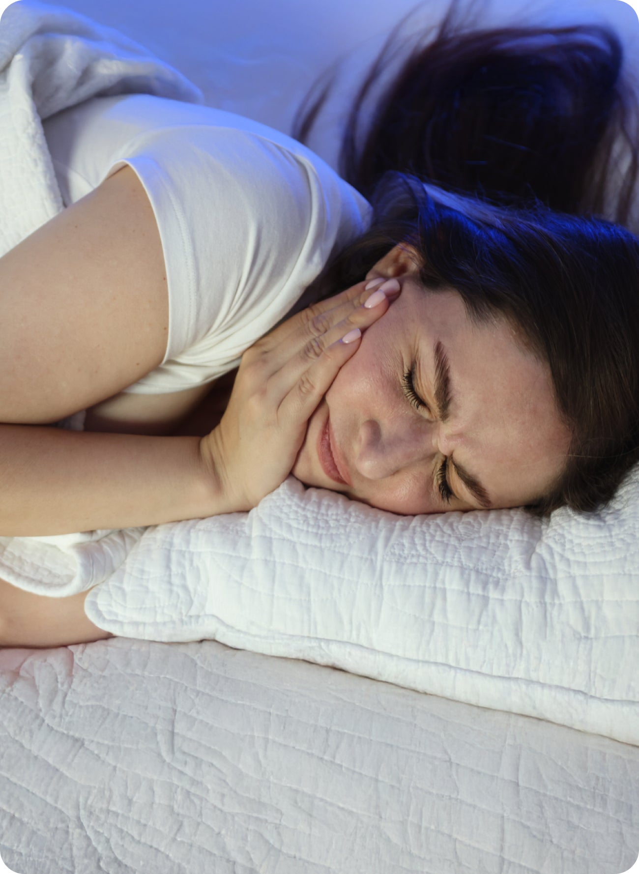 A woman is laying in bed with a toothache