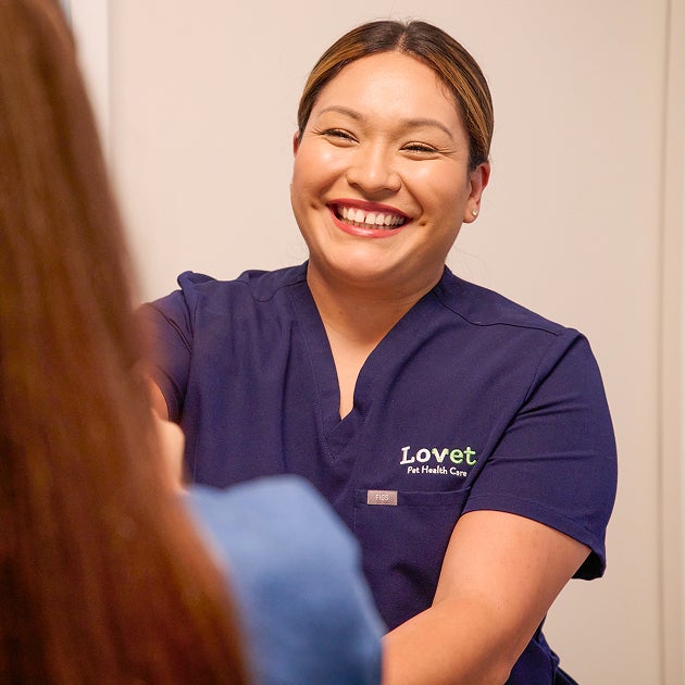 Lovet veterinary team member smiling and greeting a pet parent during a visit, creating a welcoming and supportive experience for new puppy care.