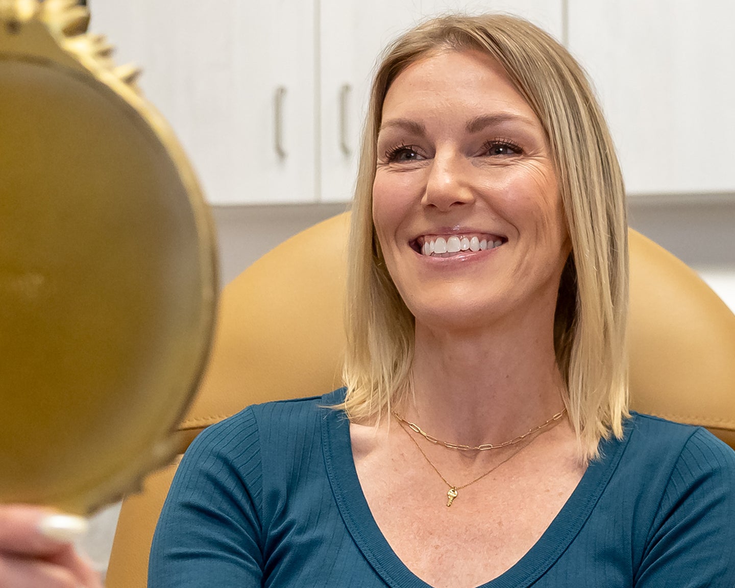 Woman smiling into a mirror after her VI Peel treatment at Chapter, highlighting the benefits of smoother, brighter skin.