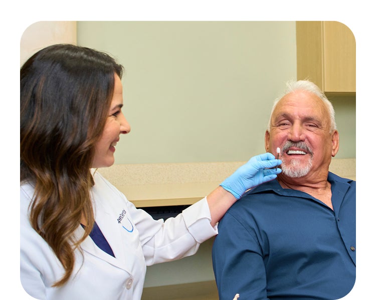 A smiling dental professional consulting with an older male patient during a veneers appointment, highlighting improving the look of your smile and personalized care.