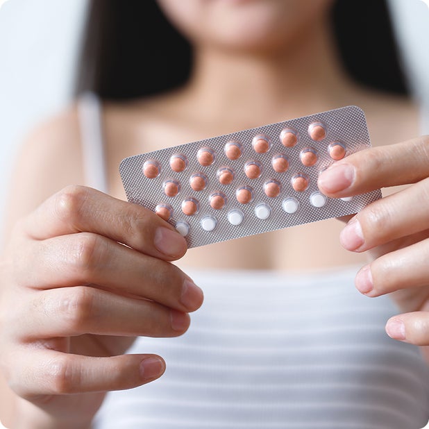 Woman holding a birth control pill blister pack, representing contraceptive services and prescription care.