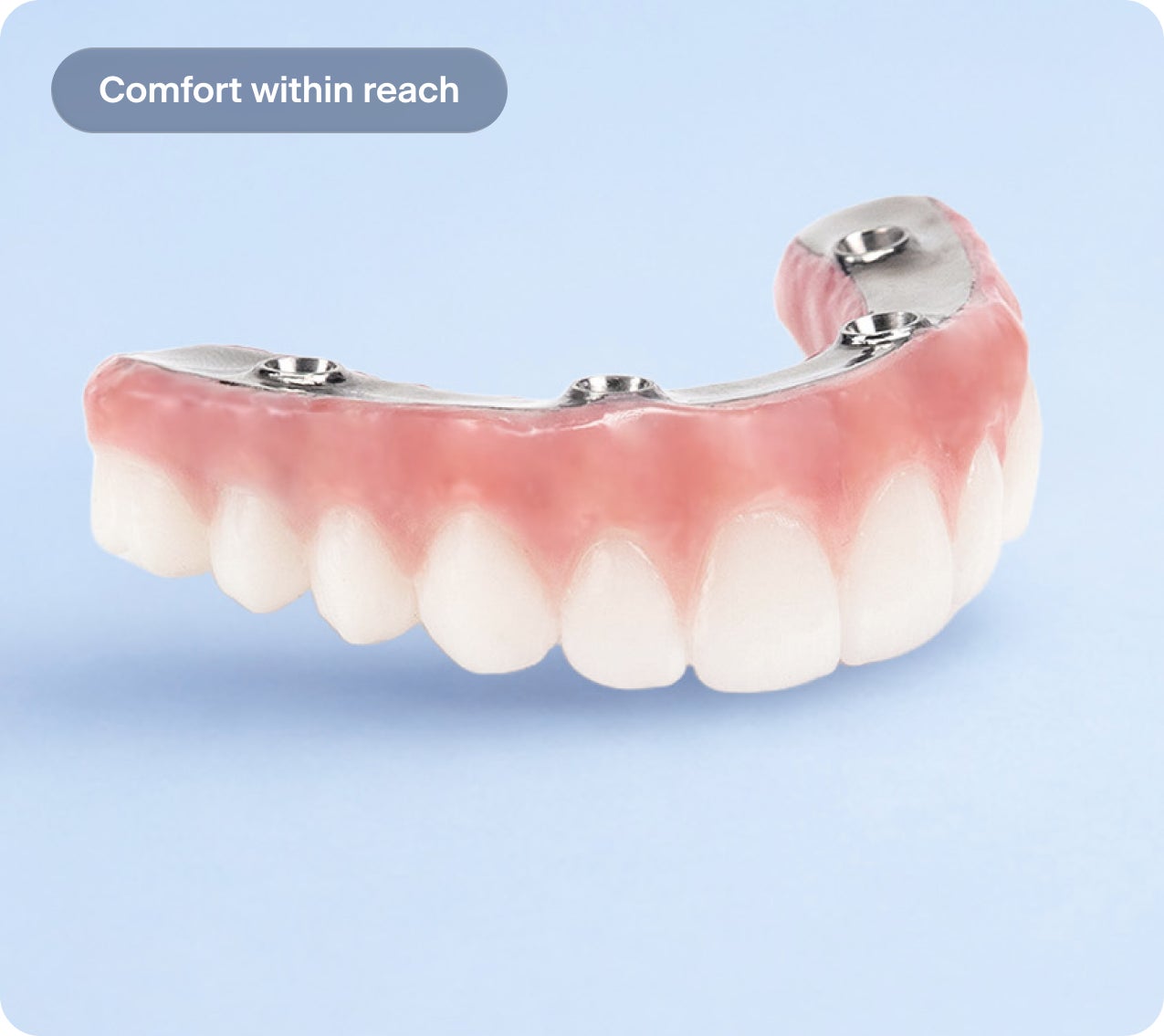 Full-arch dental implant bridge with natural-looking teeth on a light blue background. Text reads “Comfort within reach.” Image shows a fixed implant-supported arch designed for secure fit and everyday comfort.