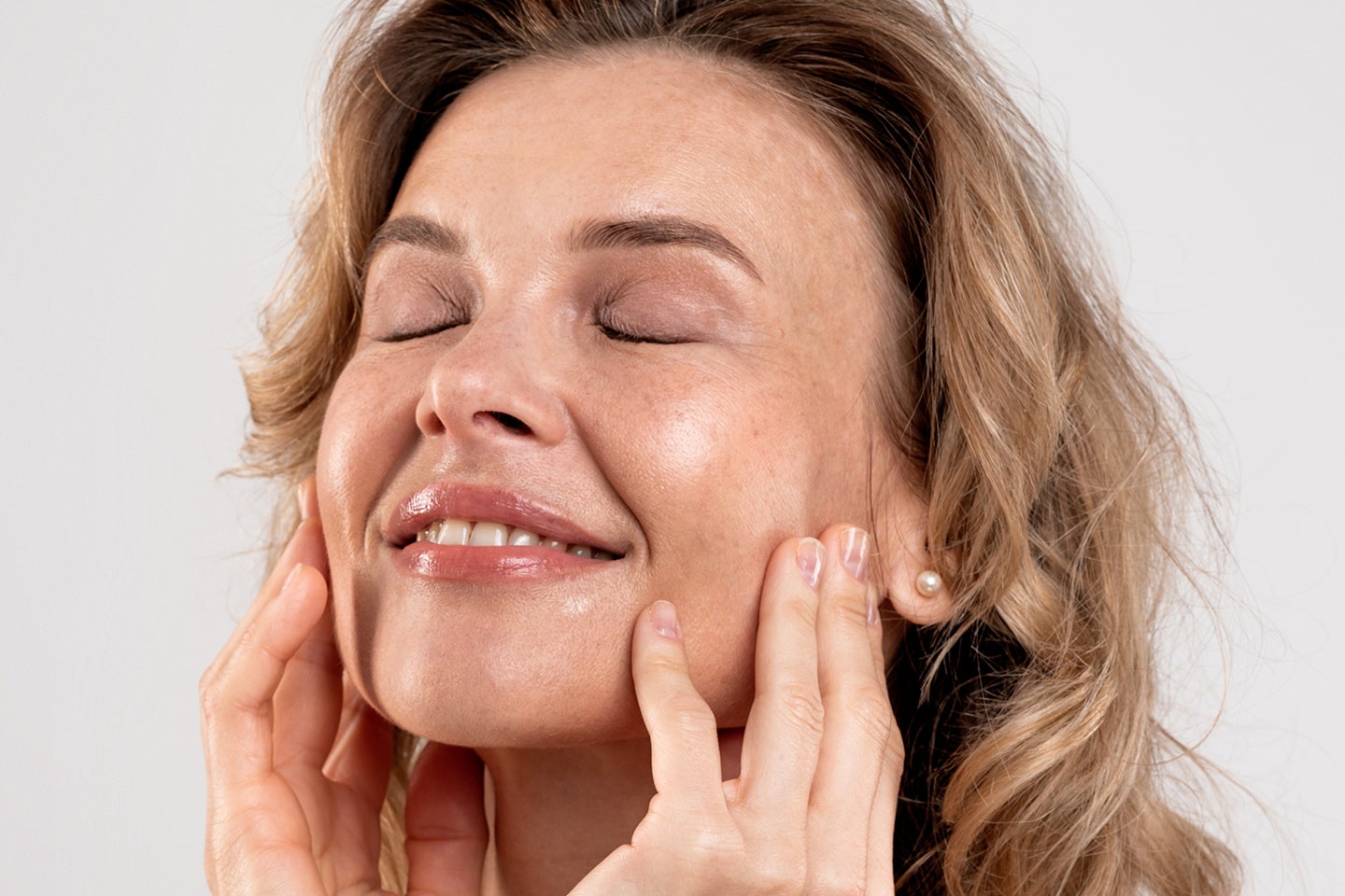 A serene woman with hands gently touching her glowing face