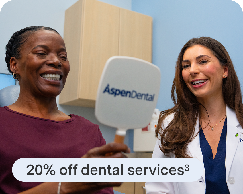 A woman smiling and looking at her reflection in a handheld mirror next to a smiling Aspen Dental doctor. A text bubble in the foreground says, "20% off dental services."