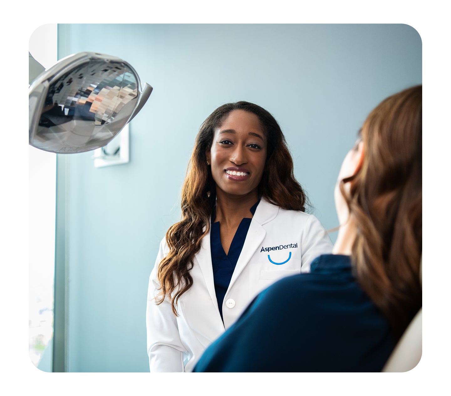 A smiling dental professional consults with a patient