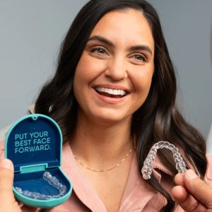 Patient smiling during a consultation while a provider shows a clear aligner, representing treatment planning with Motto