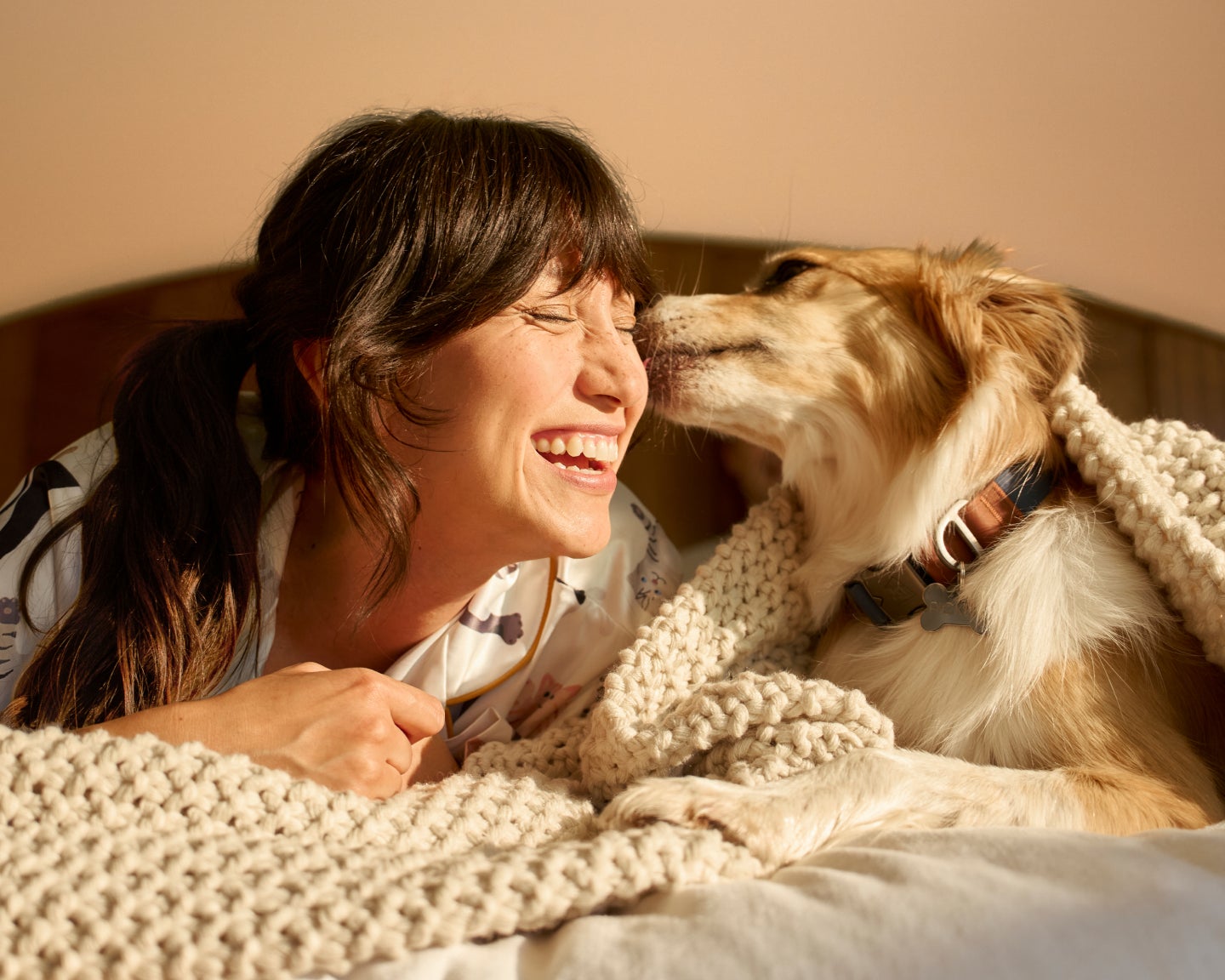 Pet parent cuddling her dog and smiling.
