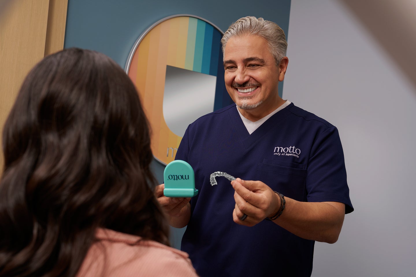 A visual of a Motto doctor handing a patient Motto clear aligners.