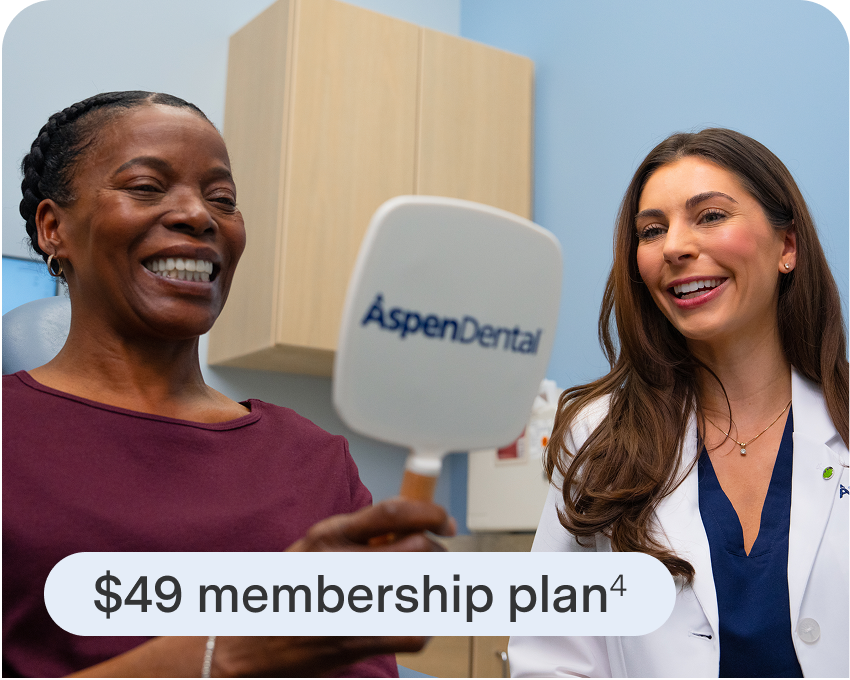 Woman smiles at her reflection in an Aspen Dental mirror next to a dental team member. A $49 membership plan is shown.