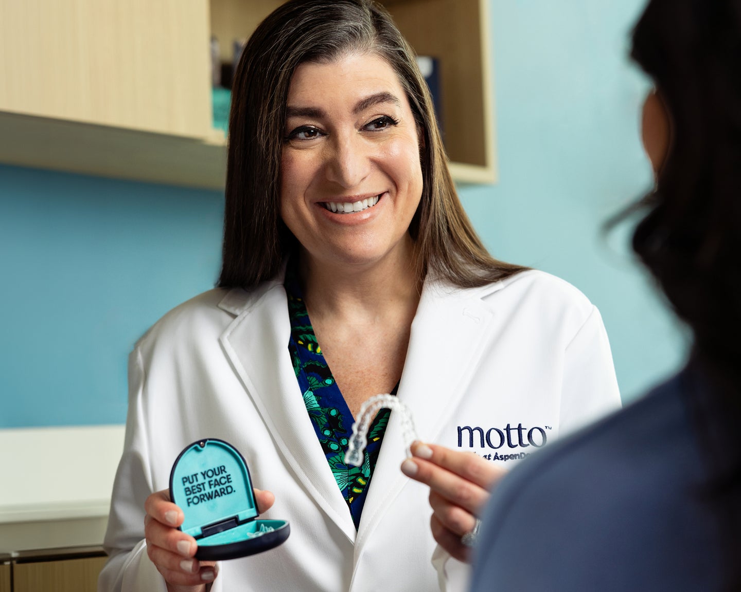 A dental professional presents a clear aligner to a patient