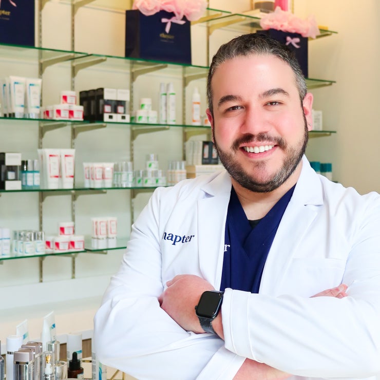 Smiling professional in a lab coat amidst skincare products