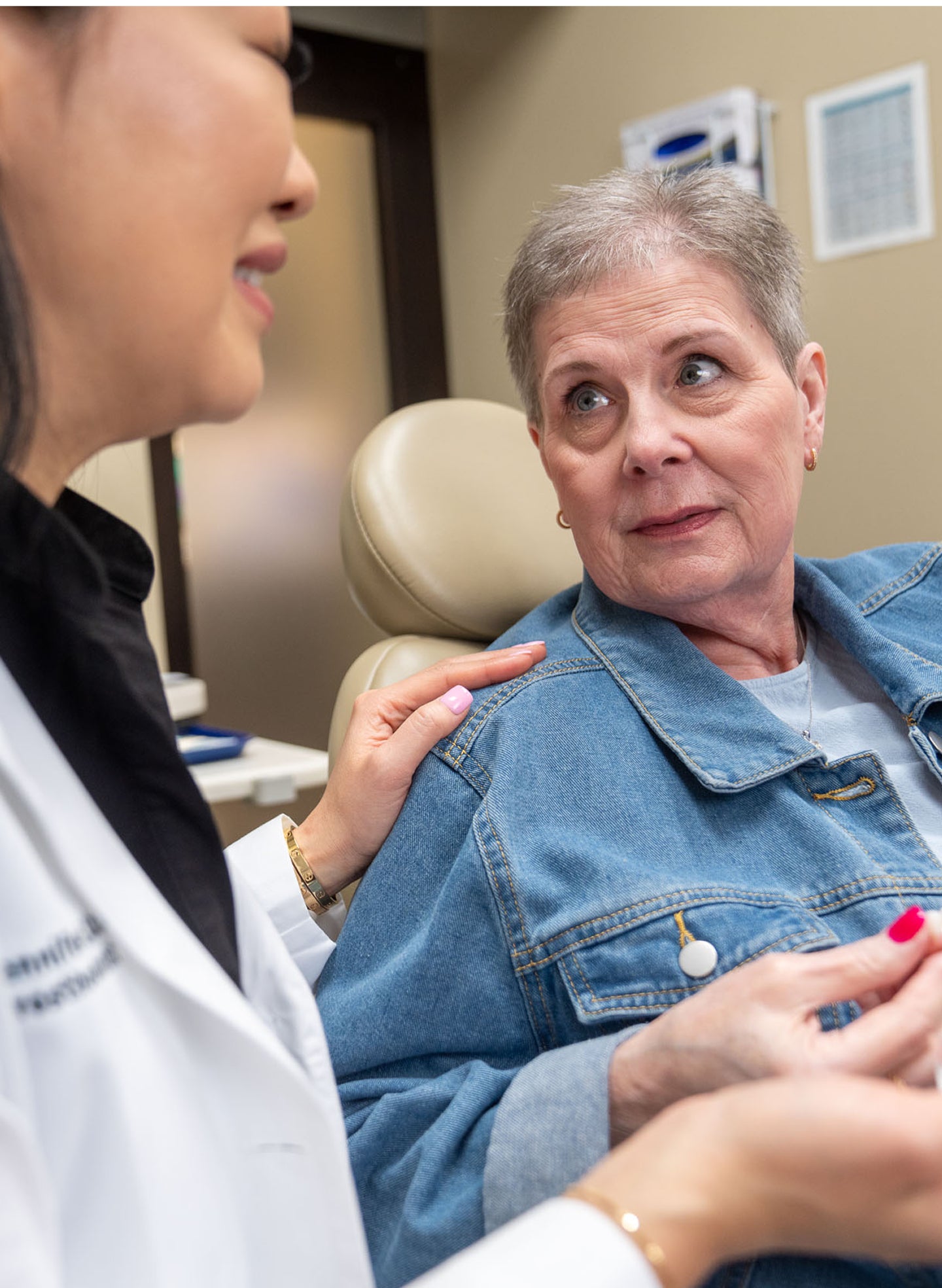 A prosthodontist gently reassures a concerned female patient while explaining dental implant options, emphasizing compassionate care when addressing delaying tooth replacement. The patient listens while holding a dental model.
