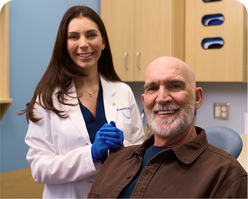 Dentist smiling with a patient during an appointment at an Aspen Dental office.