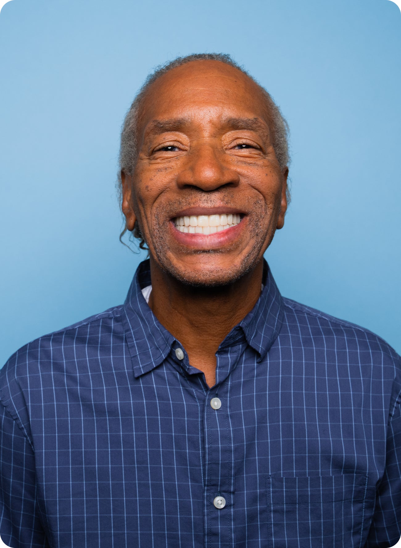Smiling man in a blue shirt against a blue background