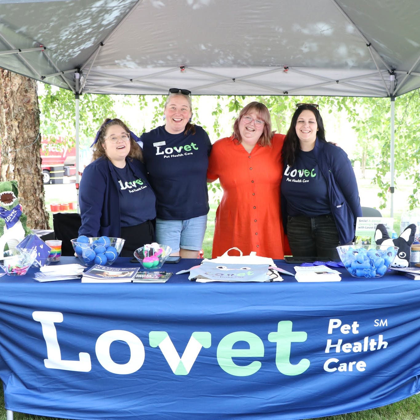 Four smiling Lovet team members gather behind a branded table at the Humane Society of West Michigan’s 143rd birthday party.