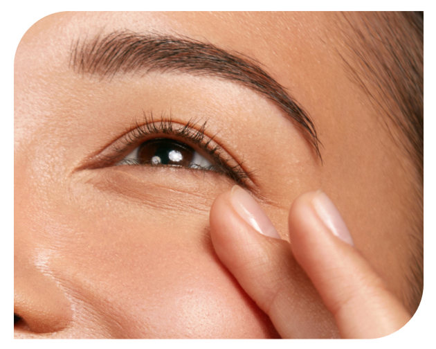 A finger gently touches the skin around an eye
