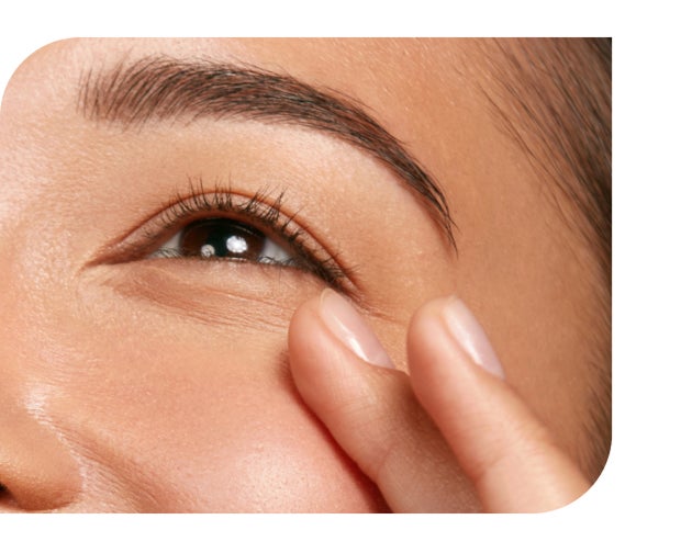 A finger gently touches the skin around an eye