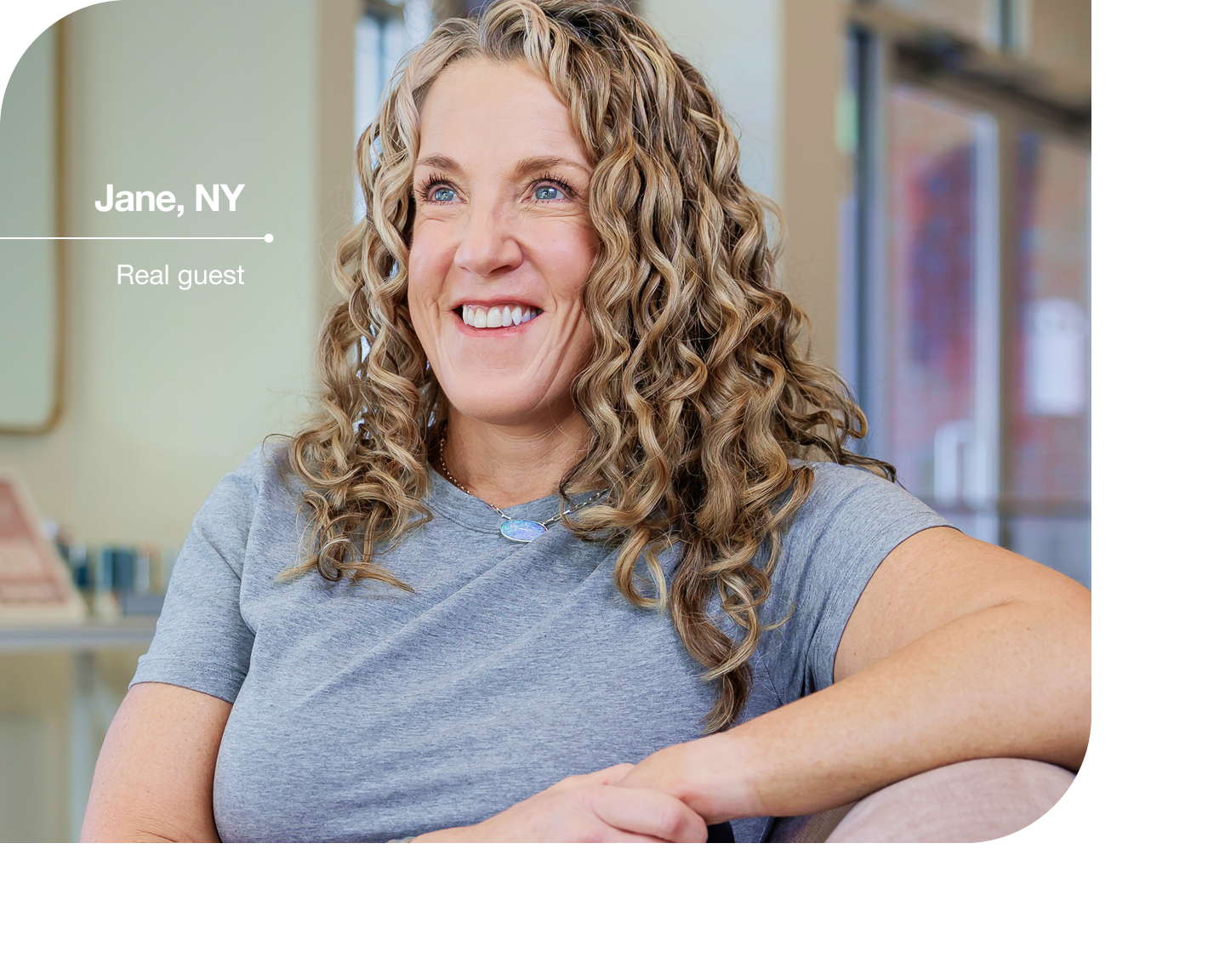 A smiling guest relaxes in a bright, welcoming aesthetic clinic during her first visit, reflecting a comfortable and judgment-free experience.