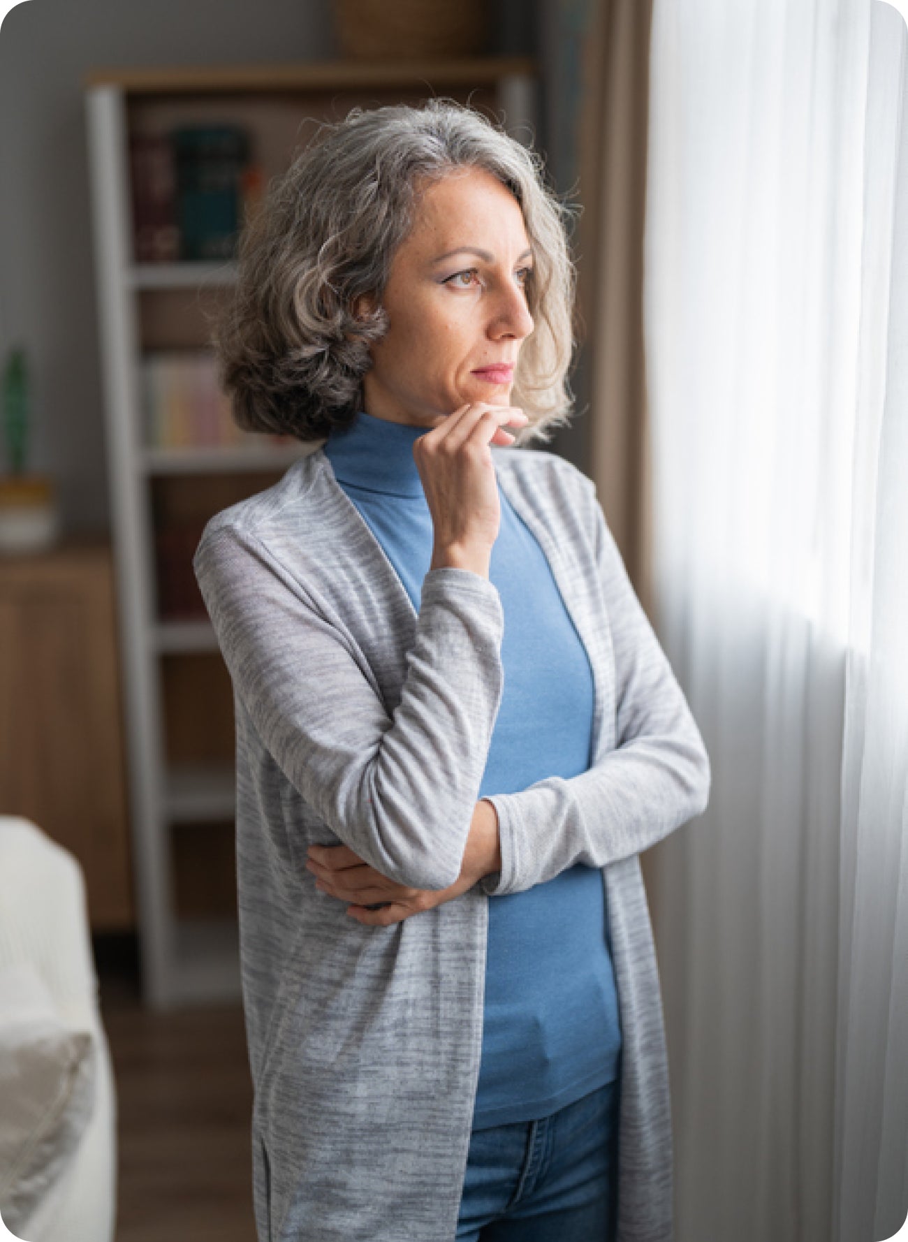 Woman standing with a thoughtful expression and touching her chin, suggesting concern about why a temporary crown feels different from a real tooth.